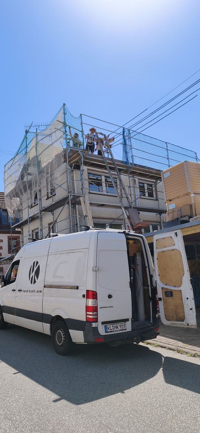Der hand-kraft-Firmenbus vor einem eingerüsteten Haus