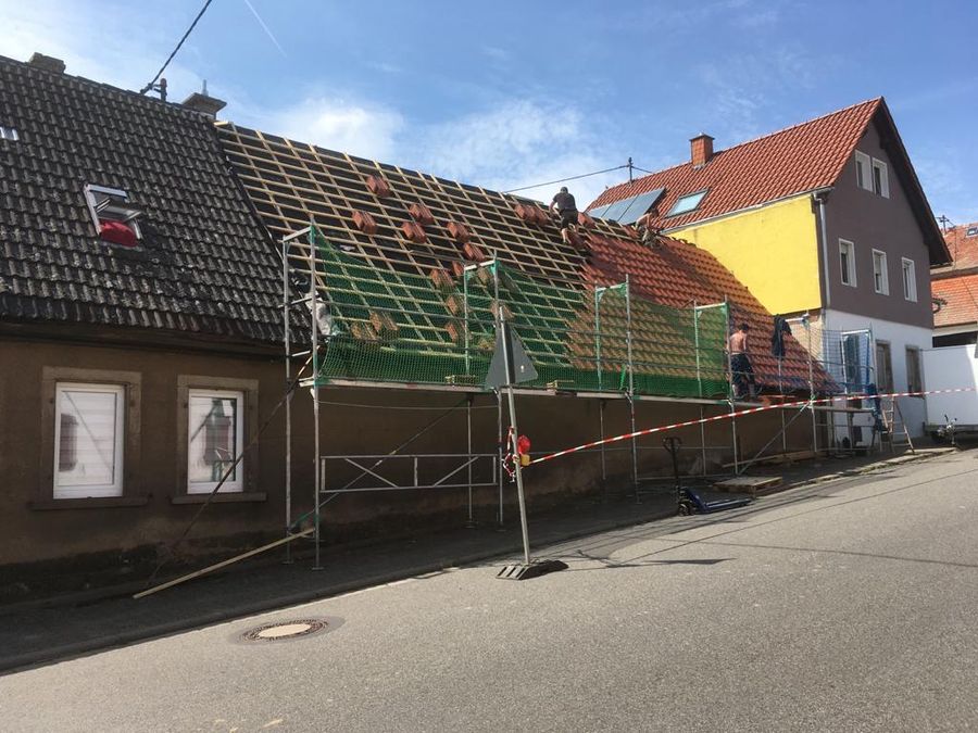 Eingerüstetes Wohnhaus an der Straße, das Dach wird neu eingedeckt
