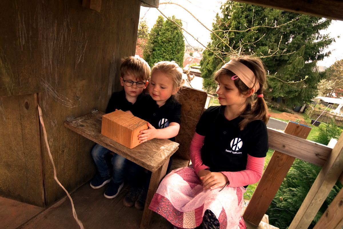 Drei Kinder in hand-kraft-Shirts im fertigen Spielhaus