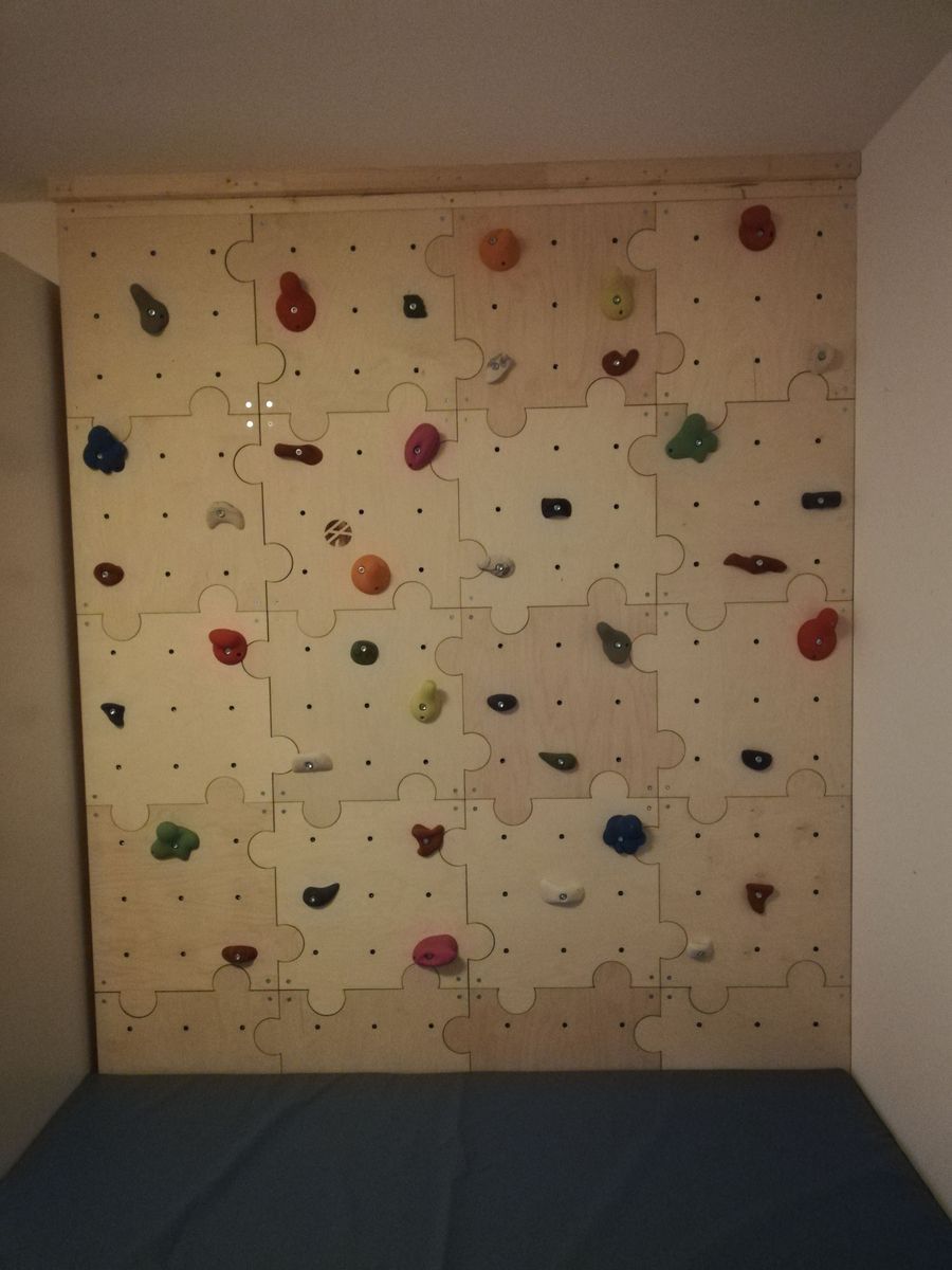 Kinderkletterwand mit vielen bunten Griffen und blauer Matte