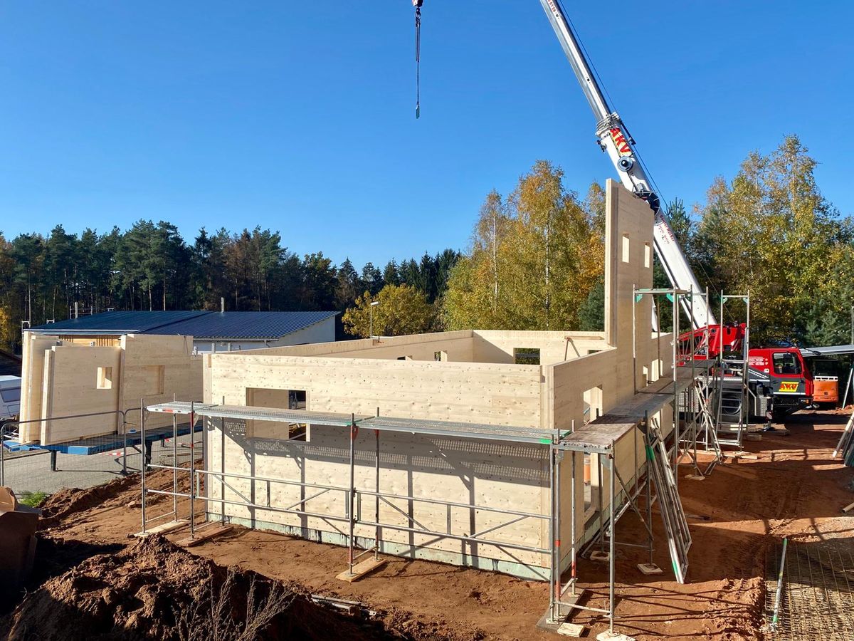 Massive Holzwand wird mit dem Kran auf die Bodenplatte gesetzt