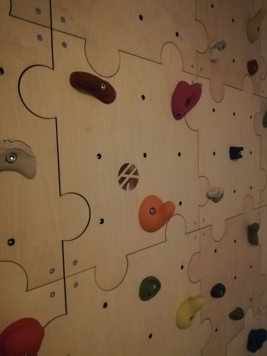 Kletterwand aus Puzzle-Modulen mit bunten Griffen