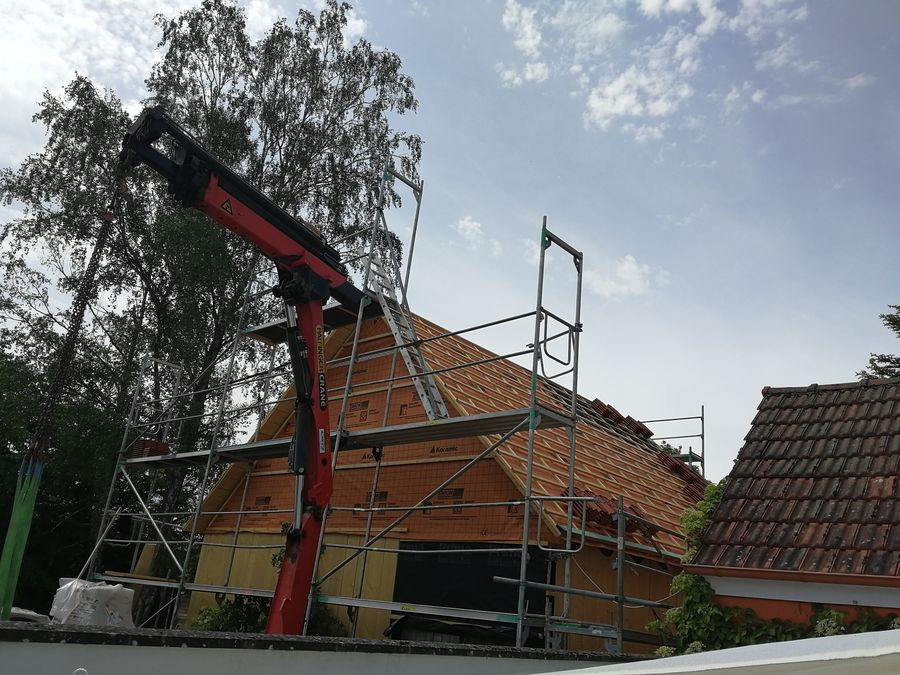 Kran hebt Dachelemente auf das neu eingedeckte Scheunendach